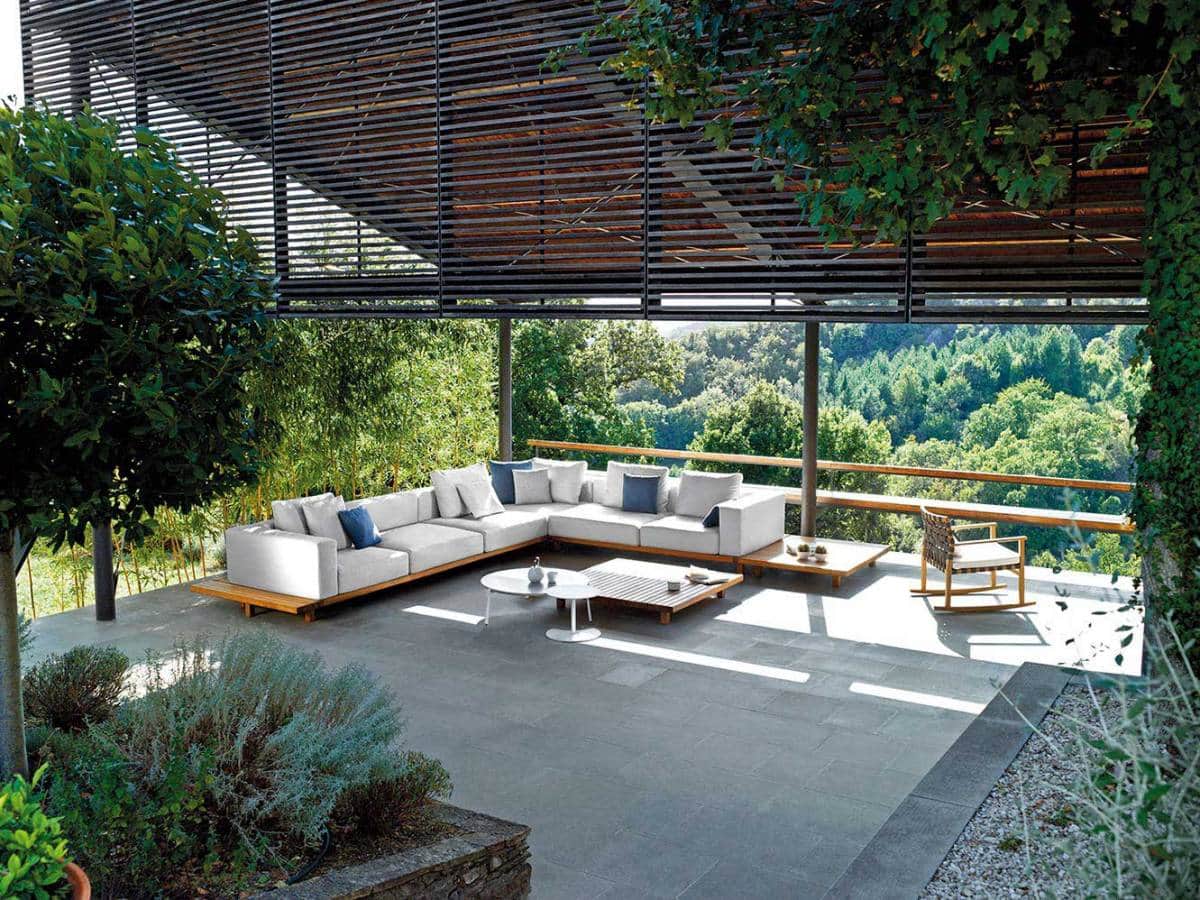 Collection modulaire comprenant un ensemble sofa, sièges et tables de jardin. Sofa à trois places, près du sol, avec assises et dossiers capitonnés piètement en bois. Design Piergiorgio Cazzaniga. ©Tribù