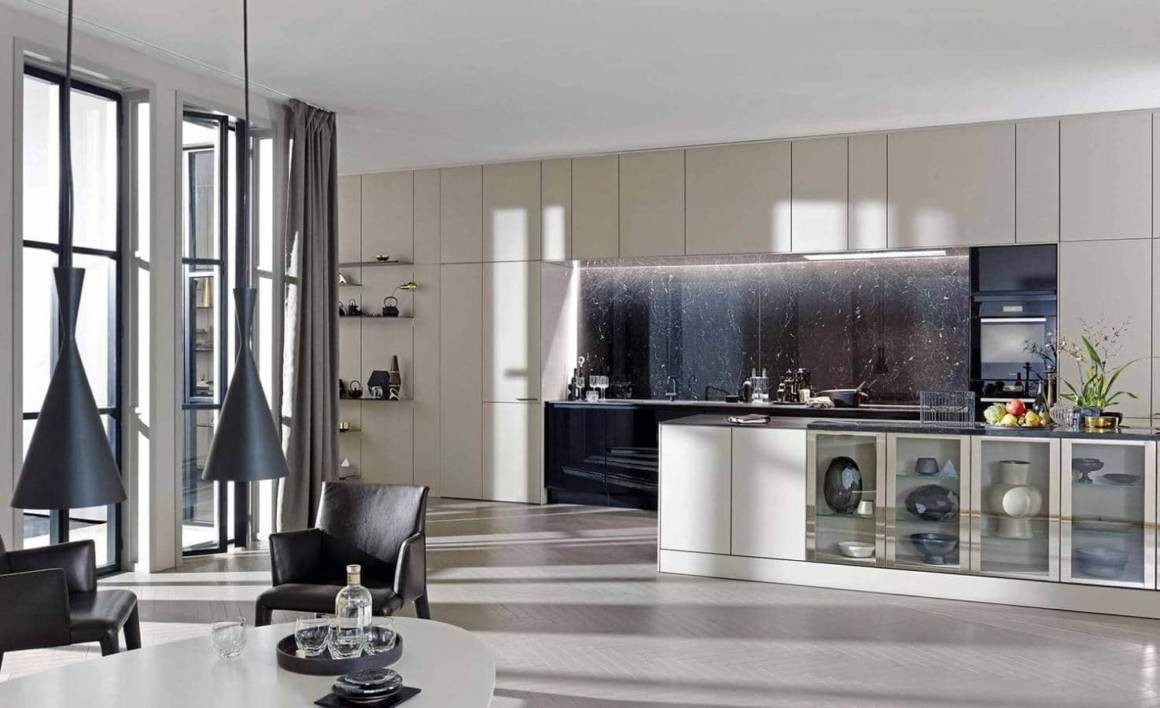 La cuisine living SE8008, mêle un caractère authentique à un esprit contemporain. Le système de panneaux et d'étagères modulables « Floating Space » crée un trait d'union tout en douceur entre le salon et la cuisine. Un jeu de niches, de portes vitrées, d'étagères décoratives, pour une ambiance équilibrée et esthétique. ©SieMatic