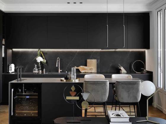 Réalisée sur-mesure par l’artisan-ébéniste, la cuisine multiplie les rangements dissimulés par les façades en FenixNTM, tandis que la crédence et le plan de travail revêtent la céramique Storm, d’Inalco. Elle s’anime grâce à la conception lumière, flattant les matériaux avec le ruban sous les modules en hauteur ou valorisant l’îlot avec le système innovant Move It de chez Xal, un rail magnétique. Lampes de table Rever Dining 1.0, Wever & Ducré. Au plafond, moulures de chez Orac Décor.