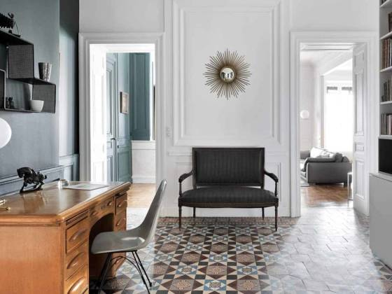 Entrée/bureau distribuant l'ensemble des espaces jour et nuit. Bibliothèque sur-mesure dessinée par l'architecte. Bureau et chaise chinés. Lampe à poser IC Lights T de Michael Anastassiades pour Flos, chez IF Contemporain. Étagère Dédal de Mathieu Matégot, Gubi. Miroir Soleil Chaty Vallauris. Peinture Silex de Ressource. En arrière plan, canapé Off Shore en cuir, de Roche Bobois