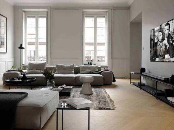 Le salon, côté rue, témoigne de la générosité du style haussmannien. Moulures et stylobates ont été conservés, à l’instar des crémones des fenêtres et de leurs shutters, les volets intérieurs bois. À la mesure de la pièce, le canapé Extrasoft (Living Divani chez Maison Hand) et l’enfilade composée du système R.I.G. (MA/U Studio), surplombée par l’écran-tableau Oled (Panasonic). Table basse en marbre Menhir (Living Divani). Table d’appoint Bowl (Mater) et tabouret (Gervasoni). Tapis berbère chiné à Marrakech (Soufiane Zarib). Lampadaire Mantis (DCW Éditions). Composition florale (Bohème Fleurs).