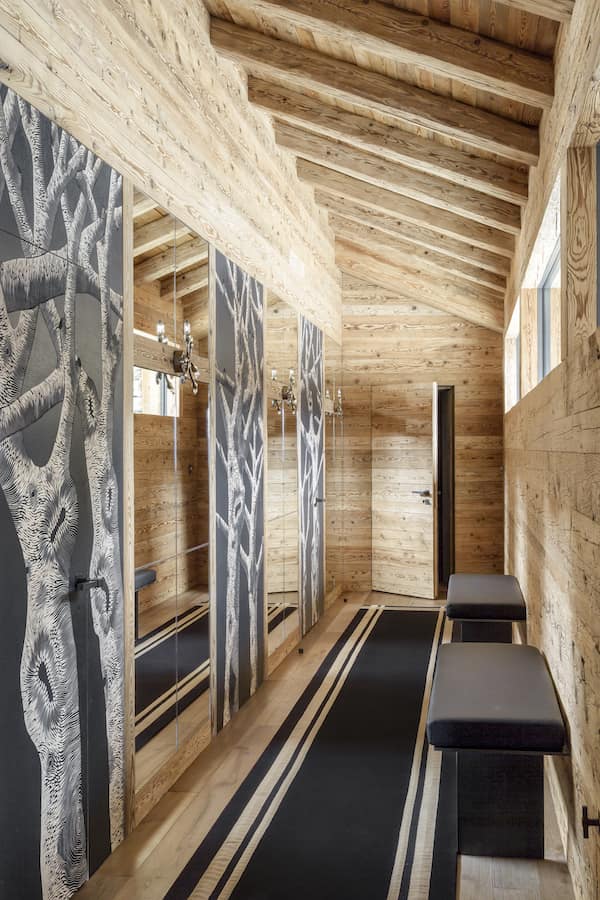 L’étage inférieur, le couloir menant au local à skis est animé par une série de panneaux en bois sculptés de motifs d’arbres par Zoé Ouvrier. Le tapis en laine et jute provient de la collection « Colportages » de la maison Arpin