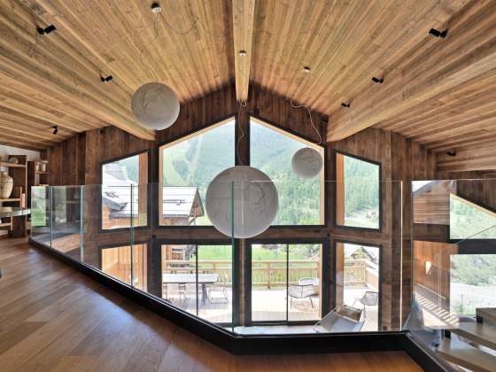 La mezzanine, comme un nid d’aigle, prend son envol. Table, Liaigre, et bibliothèque menuisée par Chalets Bayrou. Suspensions, Davide Groppi