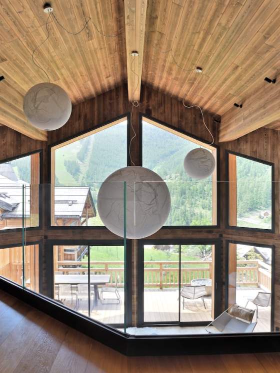 La mezzanine, comme un nid d’aigle, prend son envol. Table, Liaigre, et bibliothèque menuisée par Chalets Bayrou. Suspensions, Davide Groppi