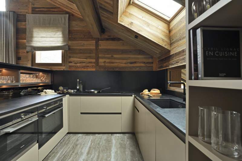 Séparée par un demi-palier, la cuisine dessinée par Maam Studio se love dans ce recoin, reliée à la salle à manger par ce meuble-vaisselier double-face