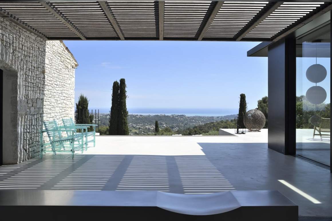 Le salon profite de la vue exceptionnelle sur la baie de Nice, sans aucun heurt visuel, tout en gardant un œil sur la pierre et le métal, connectés par cette terrasse panoramique et les fauteuils %22A’Mare%22 en lattes de polycarbonate, Edra.