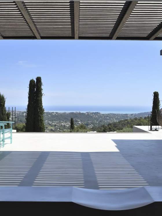 Le salon profite de la vue exceptionnelle sur la baie de Nice, sans aucun heurt visuel, tout en gardant un œil sur la pierre et le métal, connectés par cette terrasse panoramique et les fauteuils %22A’Mare%22 en lattes de polycarbonate, Edra.