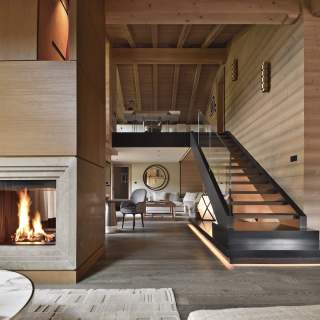 De l’autre côté, la trémie d’escalier aérienne crée cette connexion ajourée, sur son socle en pierre du Jura, avec l’étage et le salon télévision menant à la partie nocturne