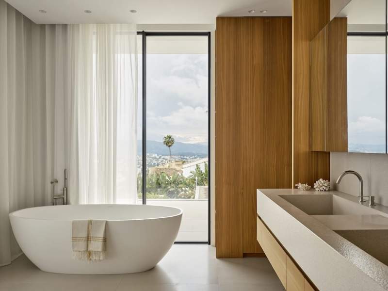 Face à la baignoire Victoria+Albert, la lumière filtre à travers les voilages, confectionnés par Atelier Dégut. Serviette en coton égyptien (Claire Gasparini). Coiffeuse Living Divani, Bel OEil