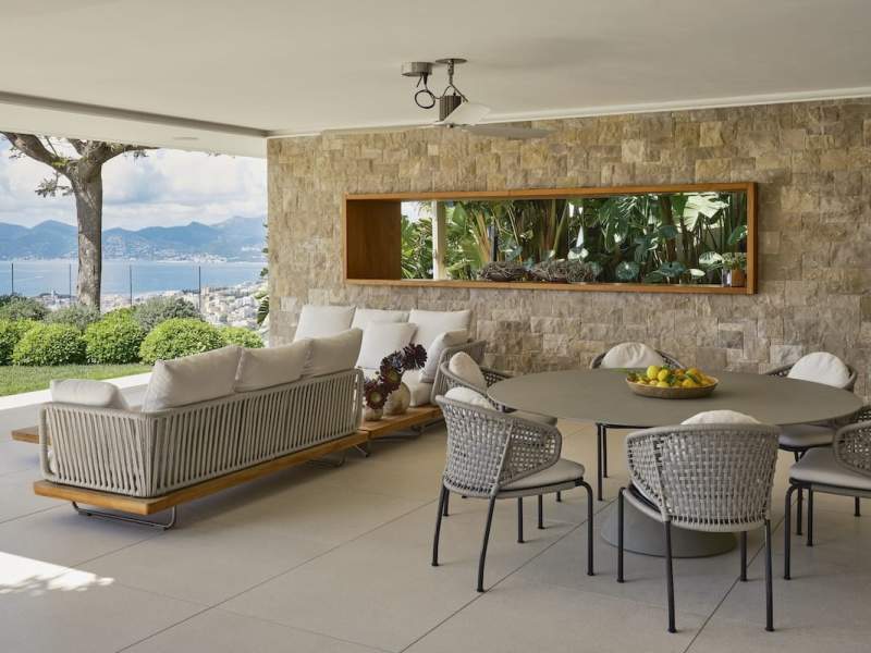 Le mobilier d’extérieur, choisi pour son confort et sa simplicité, accompagne les usages sans détourner le regard de la vue. Canapé Minotti. Plateau de fruits Claire Gasparini. Table de repas Desalto et chaises Minotti