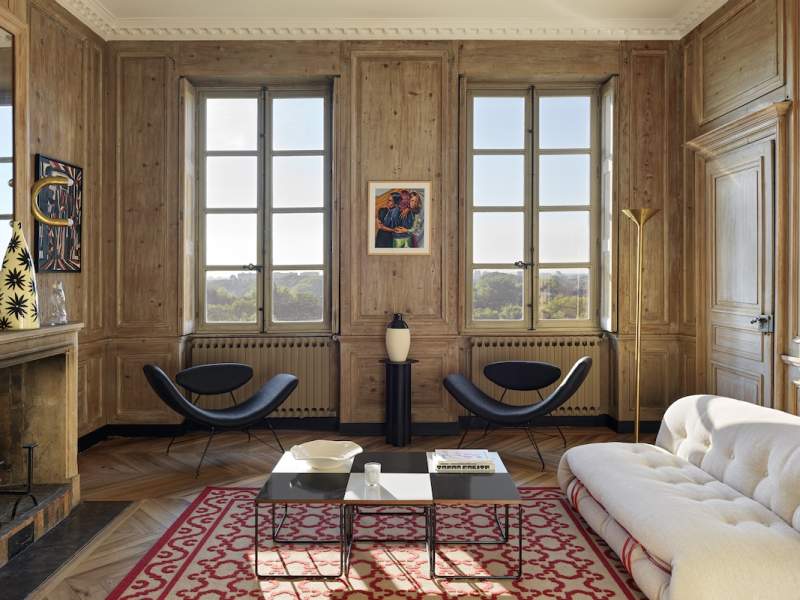 Un dialogue entre boiseries restaurées et design moderniste. Fauteuils %22Reversivel%22 (Galerie Audeamus). Table basse (Galerie 44). Canapé %22Soriana%22 (Cassina). Tapis (Casa Lopez). Lampadaire de Jacques Grange (Galerie 44). Applique (Danke Galerie)